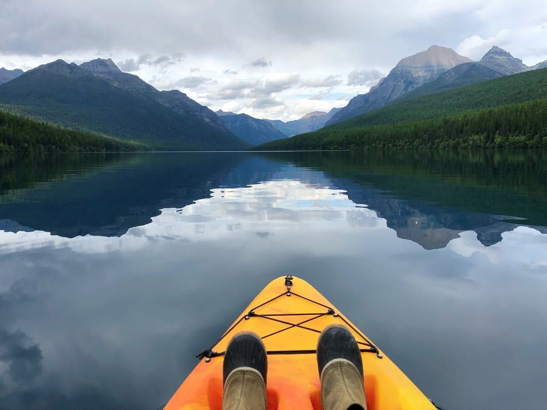 calm kayaking experience on the Stillwater River with reflections of the mountains and sky on the glassy water. Ideal for a peaceful outdoor adventure.