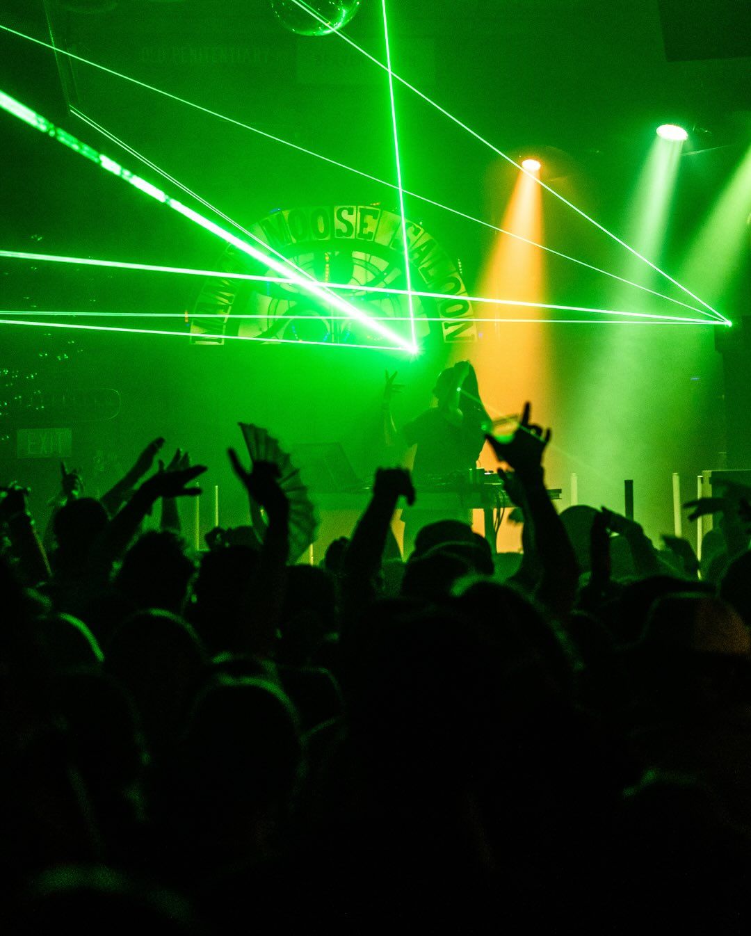 A DJ performs on stage at The Mangy Moose while the crowd raises their hands under purple concert lights. This popular après-ski spot in Teton Village is famous for live music, DJs, and unforgettable nights after the slopes close.