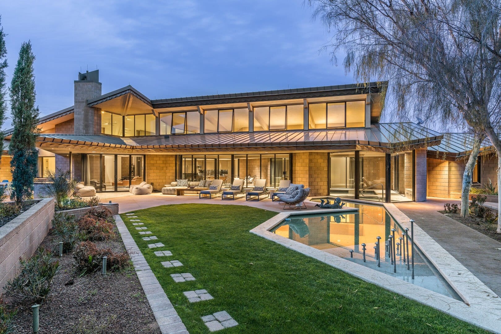 Modern estate with expansive glass walls, sleek architecture, and a serene outdoor oasis with a reflecting pool.
