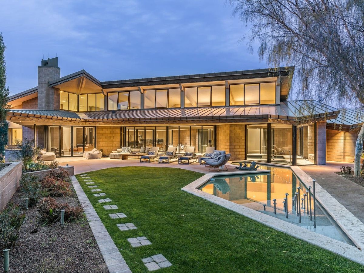 Modern estate with expansive glass walls, sleek architecture, and a serene outdoor oasis with a reflecting pool.