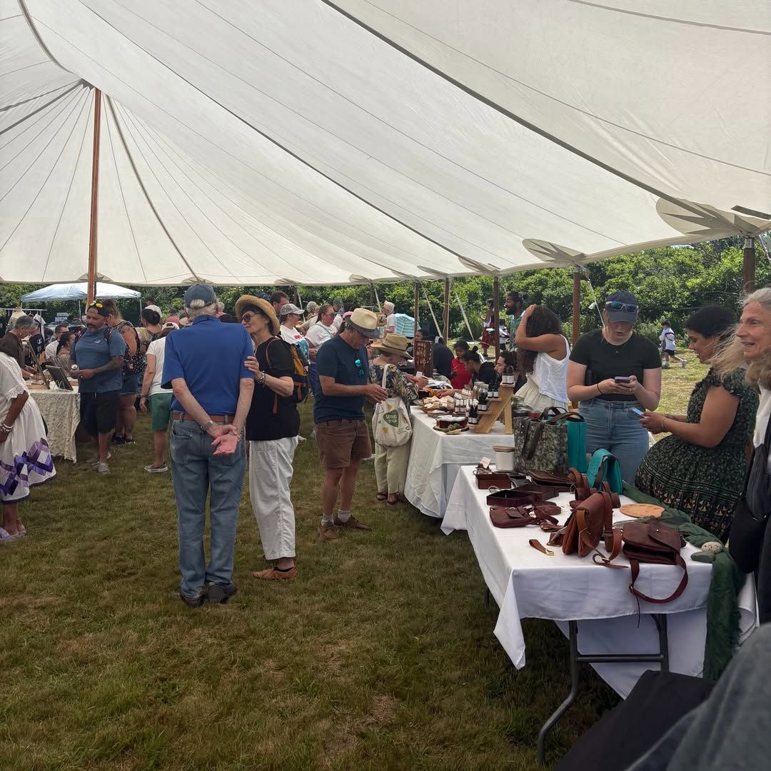 Under a large white tent, islanders and visitors browse tables filled with handcrafted goods at the Native Artisan Market & Festival in Aquinnah. The event celebrates local creativity, Indigenous heritage, and a warm community spirit.