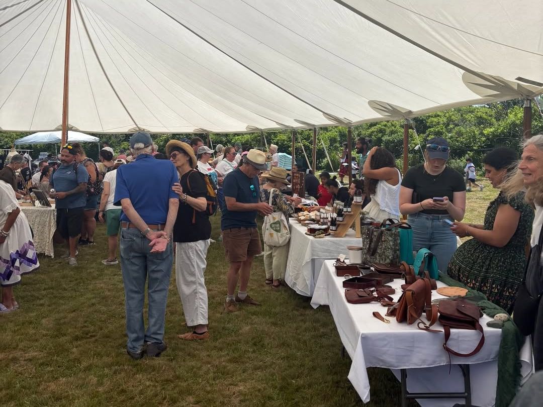 Under a large white tent, islanders and visitors browse tables filled with handcrafted goods at the Native Artisan Market & Festival in Aquinnah. The event celebrates local creativity, Indigenous heritage, and a warm community spirit.