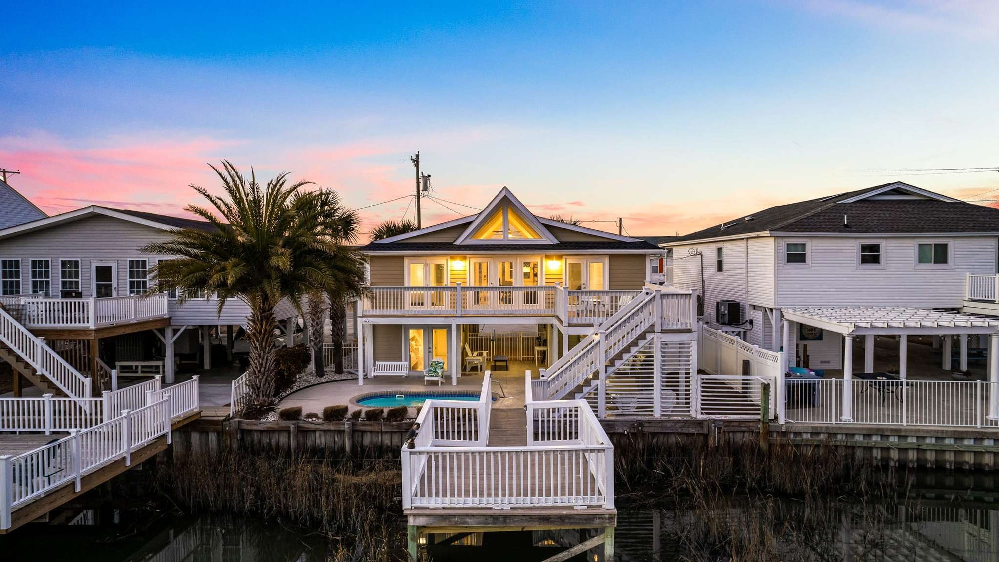 With its grand double-deck design overlooking the channel, this waterfront getaway blends elegance and comfort. Guests can unwind in the private pool or enjoy the evening glow from the upper balcony as the sky turns pink.