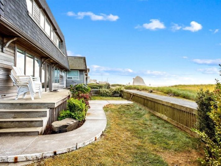 A private beachfront yard with a paved walkway leading directly toward the shoreline and sand dunes. This outdoor space makes beach access easy while offering a peaceful spot to enjoy the fresh coastal air.