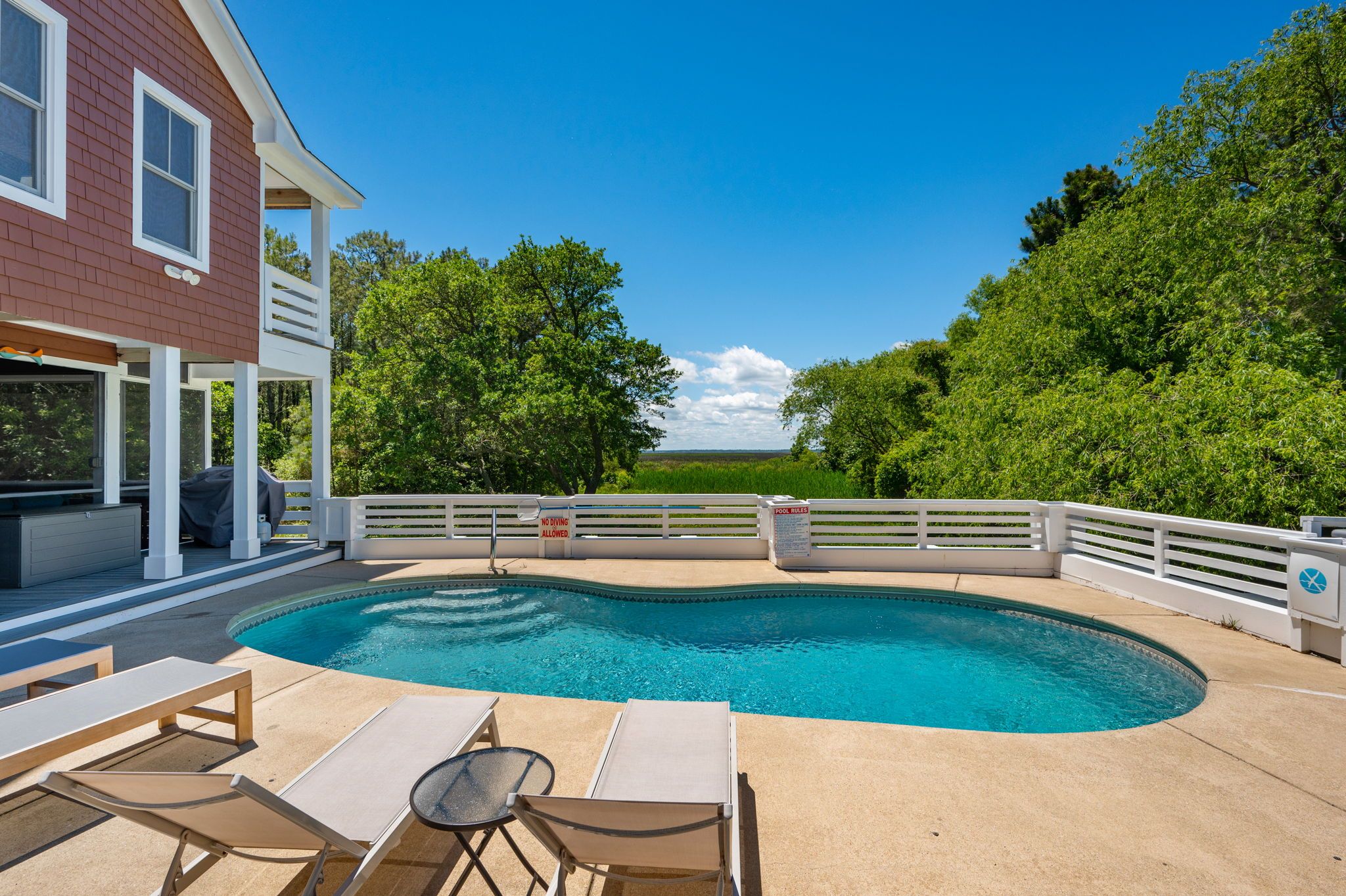 Private pool at home with white fence surrounding it and lounge chairs