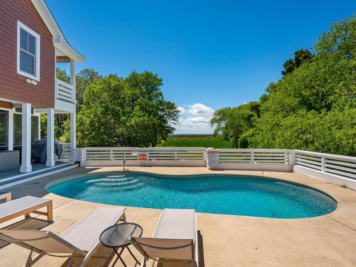 Private pool at home with white fence surrounding it and lounge chairs