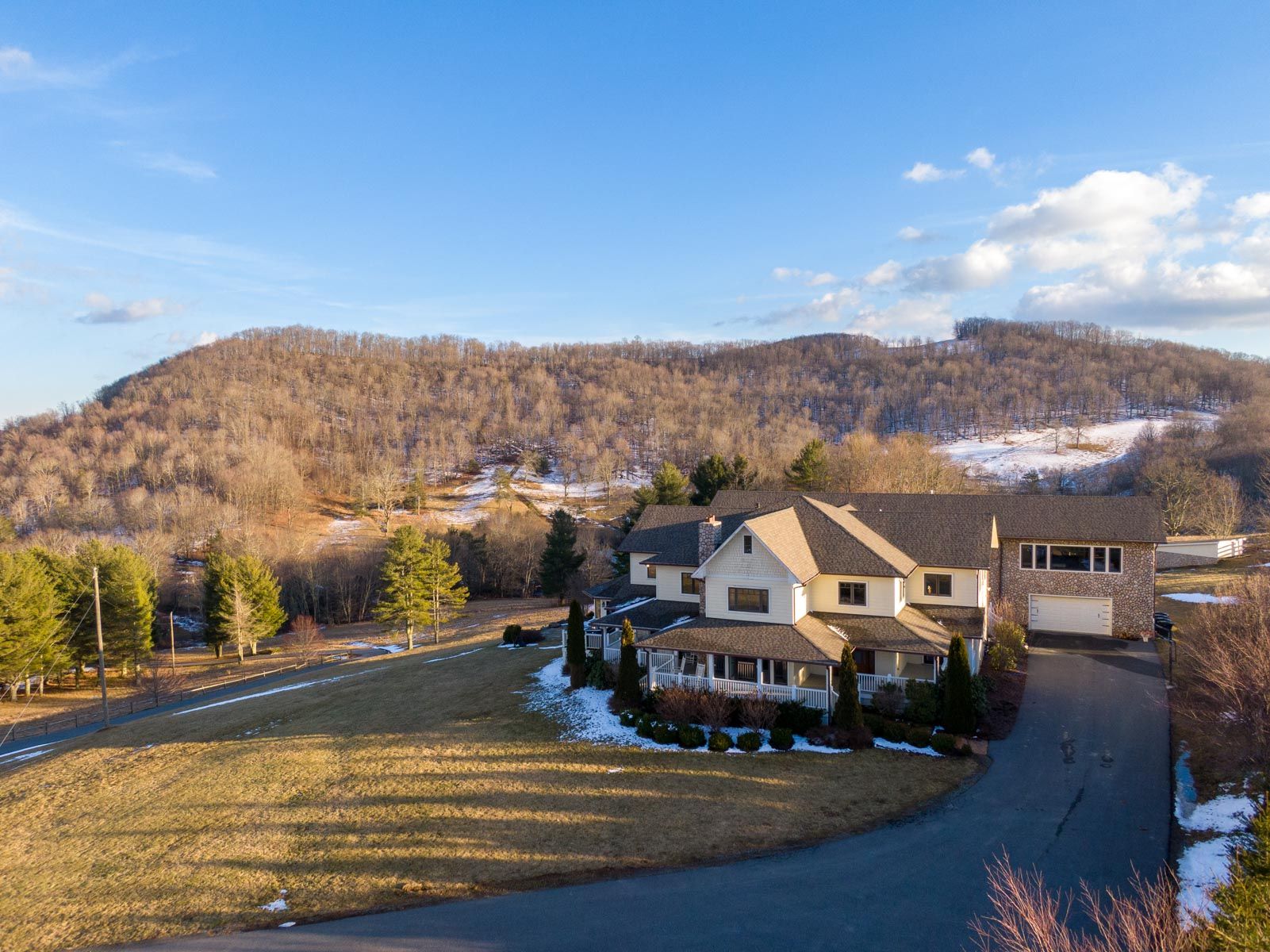 Exterior of large vacation rental in north carolina with light snow at the bottom surrounded by mountains