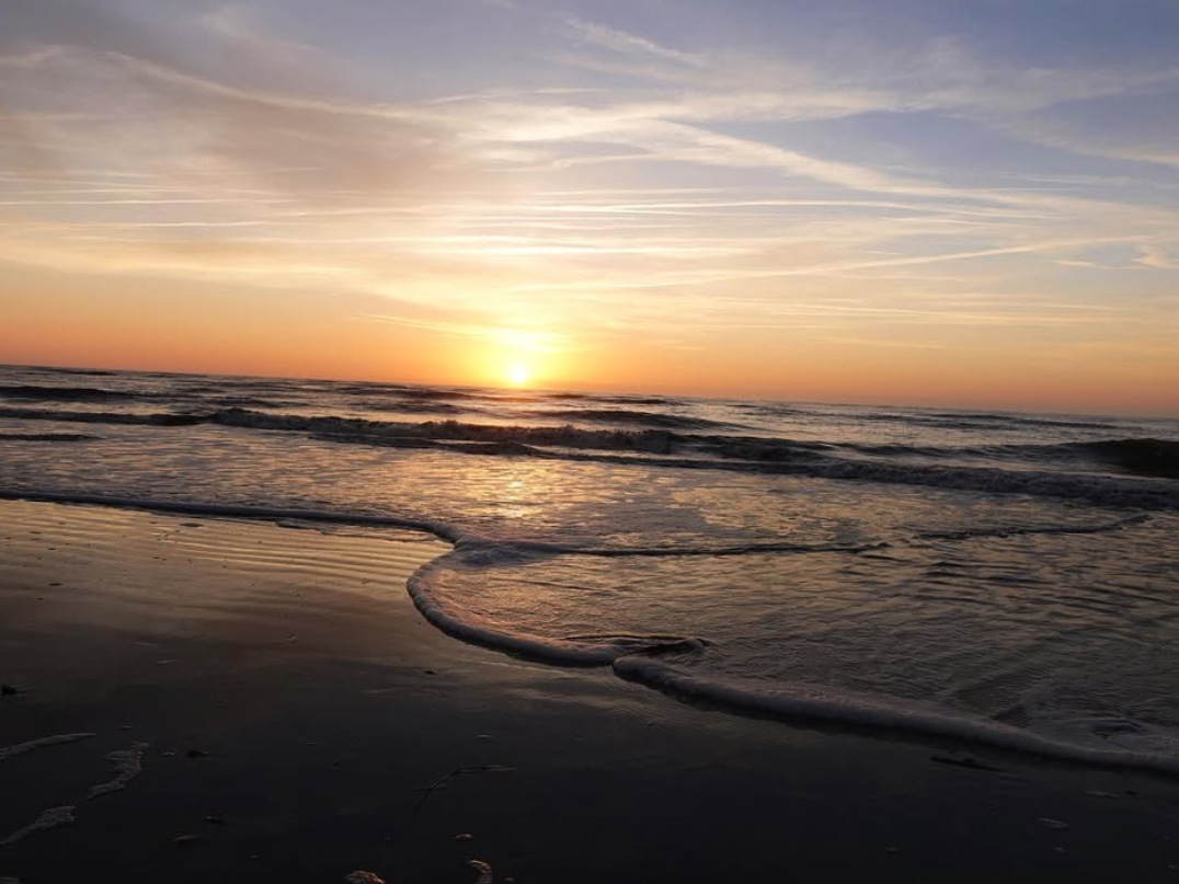 Orange and blue sunset skies reflecting on ocean water at beach in St Simons Island