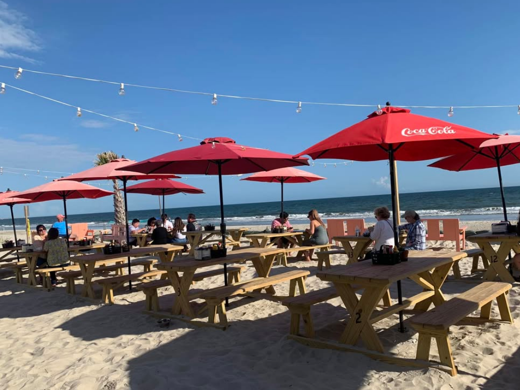 Wooden picnic tables with red umbrellas with coca cola sign on it
