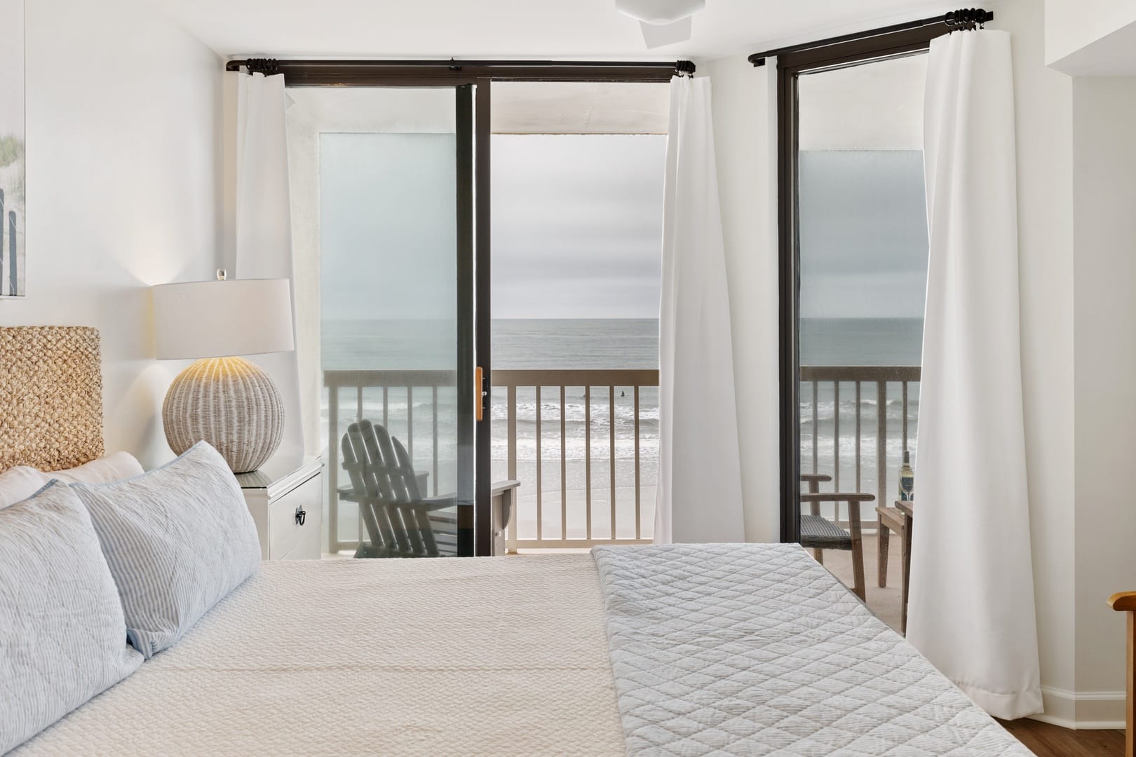 Bedroom views with large open windows and balcony with beach views