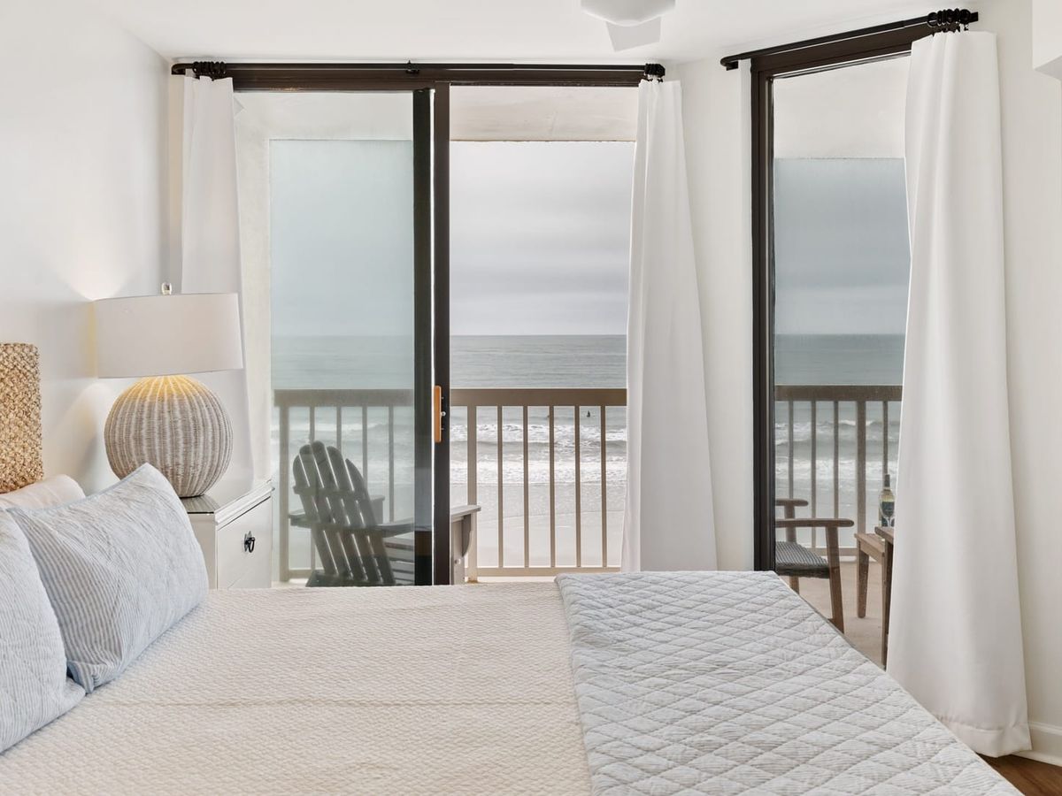 Bedroom views with large open windows and balcony with beach views