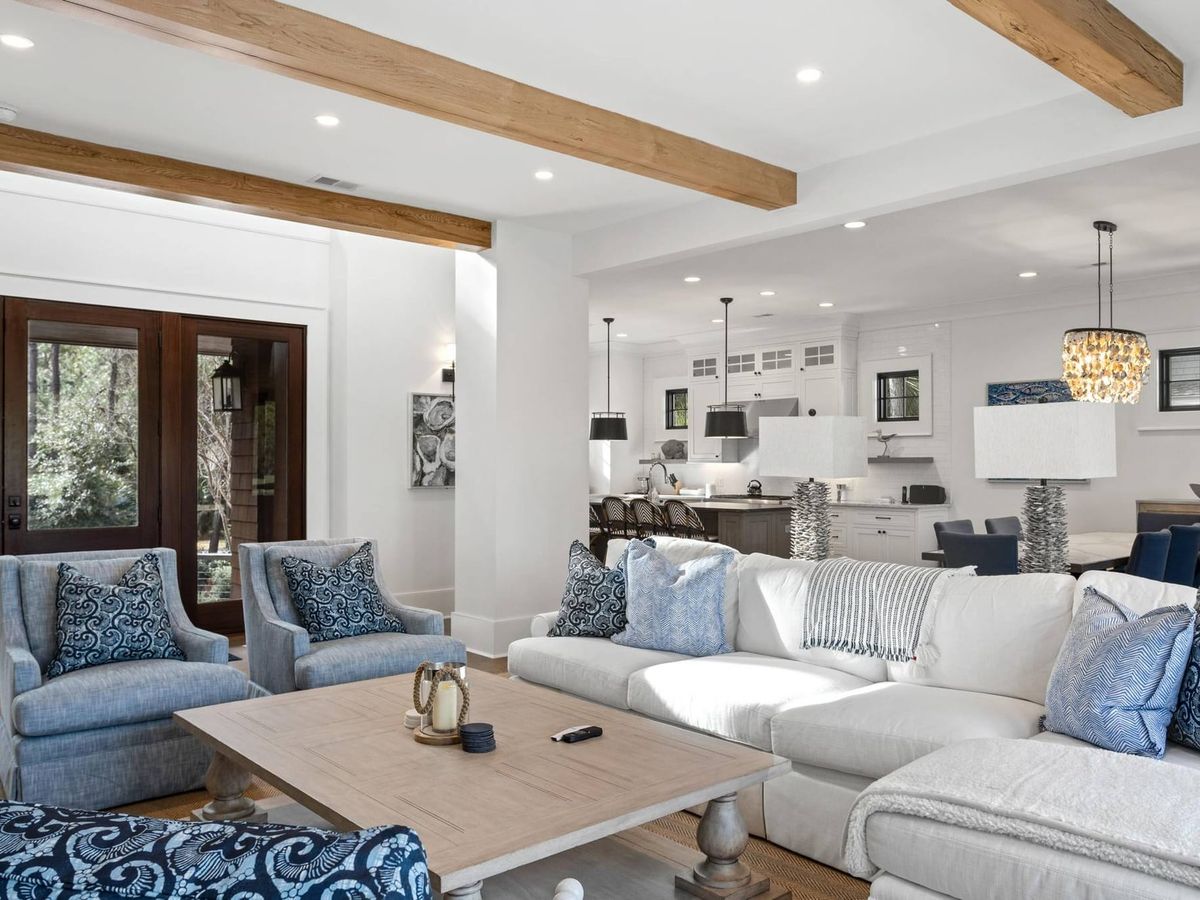 Bright and airy living space with soft blue accents and an open floor plan connecting the kitchen, dining, and lounge area. Perfect for families looking for comfort and style during their Kiawah Island getaway.