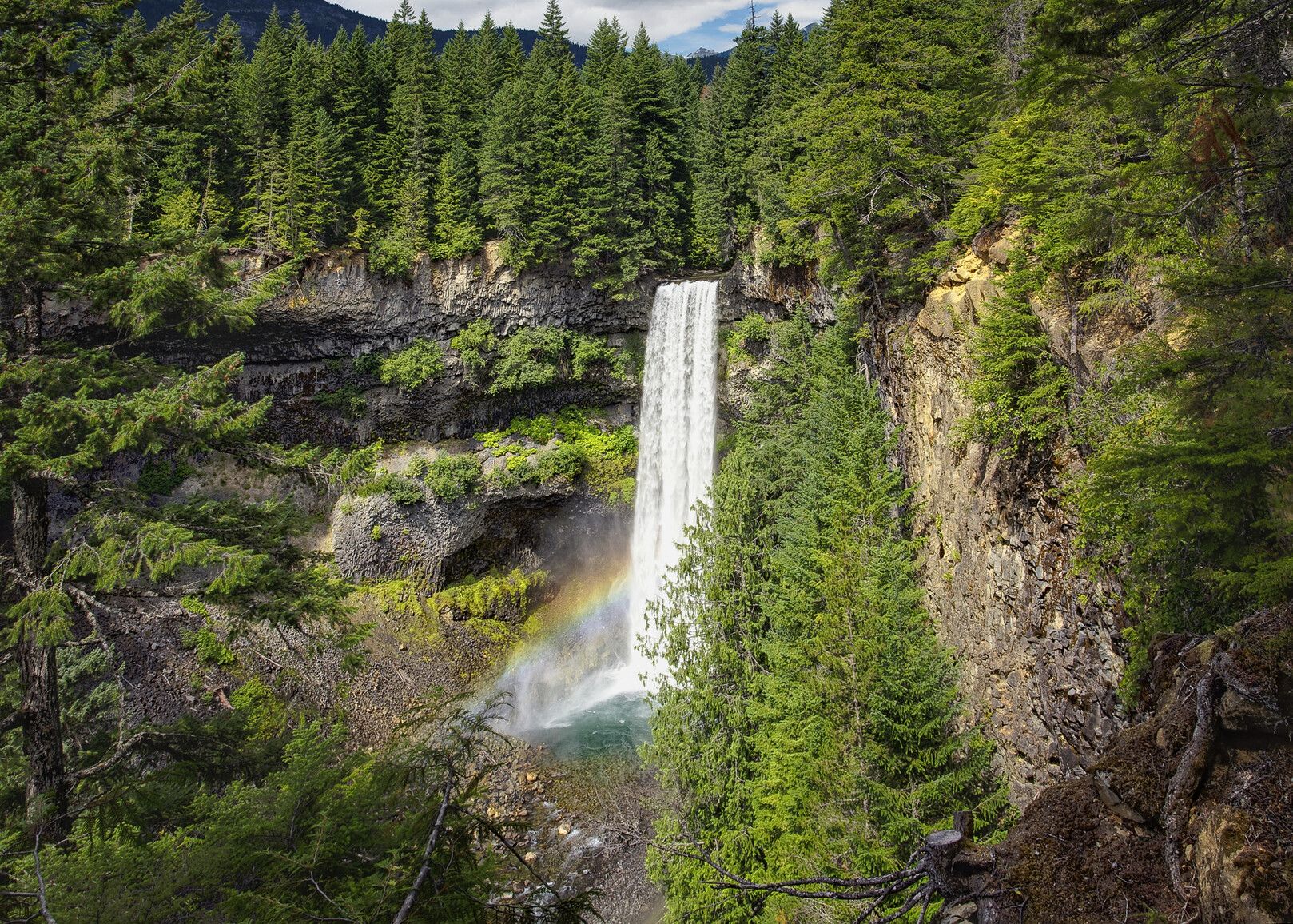 Brandywine Falls cascades down a dramatic cliff surrounded by lush evergreen forest in Whistler, BC. A soft rainbow forms in the mist at the base, adding to the magic of this iconic waterfall. It’s one of the most scenic stops along the Sea-to-Sky Highway and a must-see nature spot near Whistler.