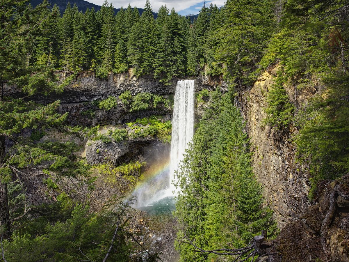 Brandywine Falls cascades down a dramatic cliff surrounded by lush evergreen forest in Whistler, BC. A soft rainbow forms in the mist at the base, adding to the magic of this iconic waterfall. It’s one of the most scenic stops along the Sea-to-Sky Highway and a must-see nature spot near Whistler.