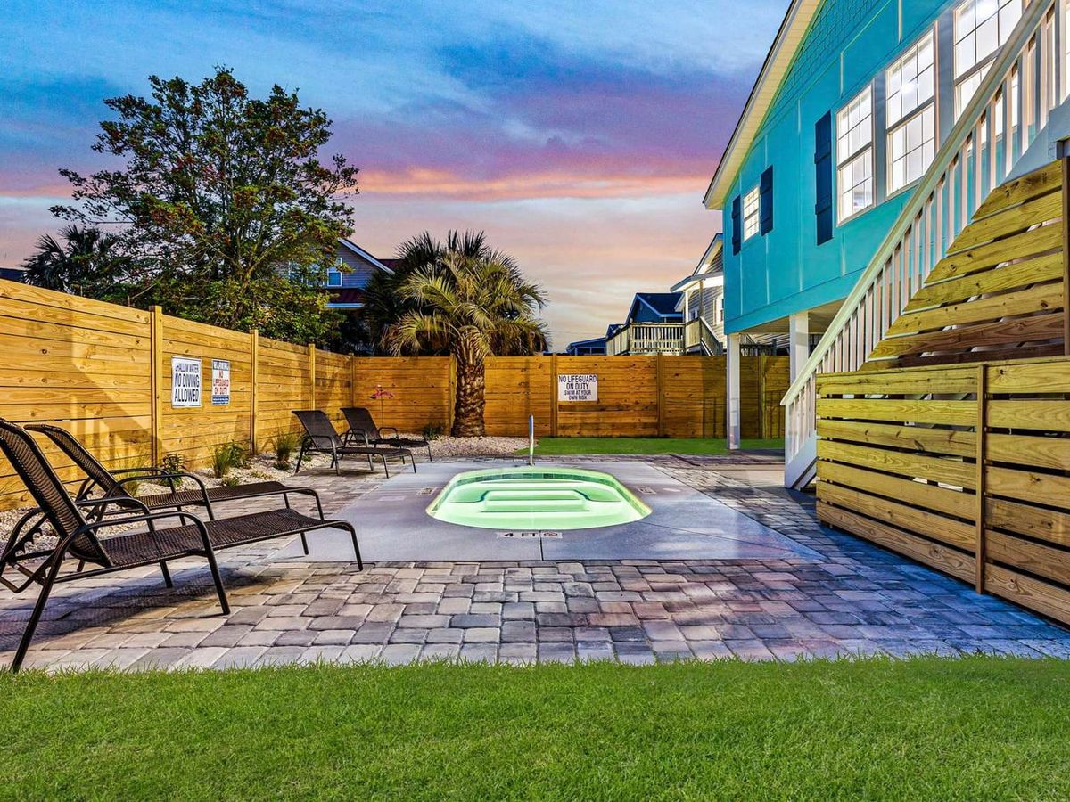 This private pool retreat offers the perfect mix of fun and privacy with tropical palms, modern loungers, and a cozy fenced yard. The glowing pool invites guests to enjoy warm Carolina evenings under the stars.