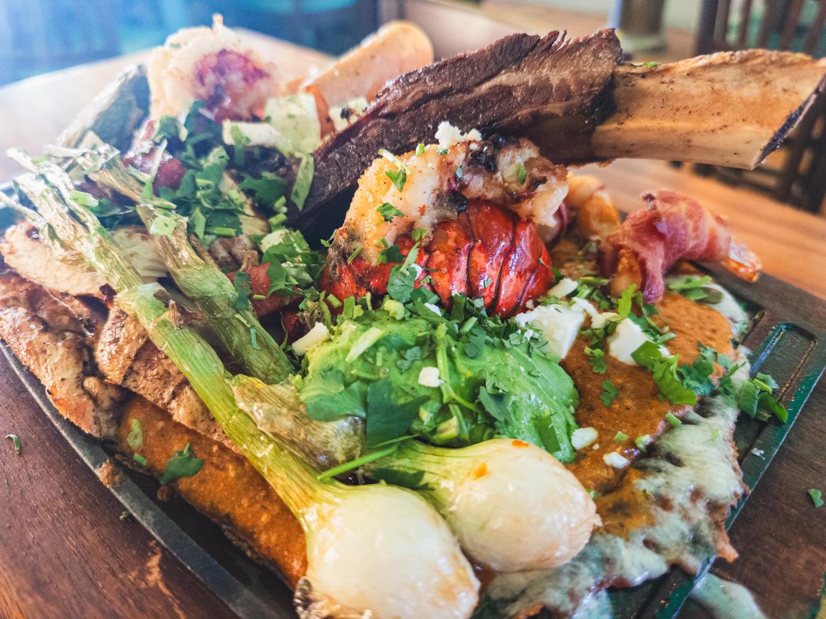 A sizzling plate loaded with grilled meats, shrimp, and vegetables, topped with fresh herbs at Casa de Fred’s Tacos y Tequila. This hearty dish shows off the bold and flavorful Mexican cuisine San Diego is known for.