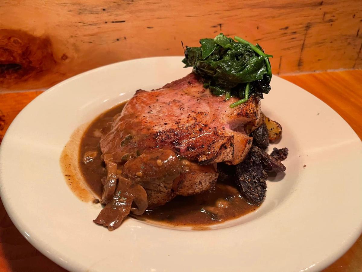 Juicy bone-in pork chop served over roasted potatoes with caramelized onions and greens at Casey’s Caboose. The warm brown gravy and rustic presentation make it a classic Vermont comfort meal. This cozy Killington dining spot is loved for its relaxed vibe and hearty mountain dishes.