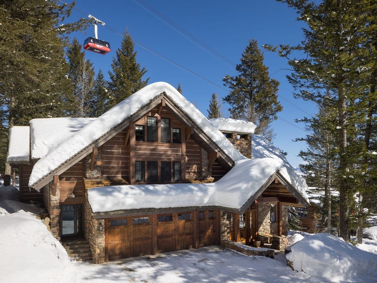Snow-covered cabin with snowy driveway in Jackson Hole underneath aerial tramway