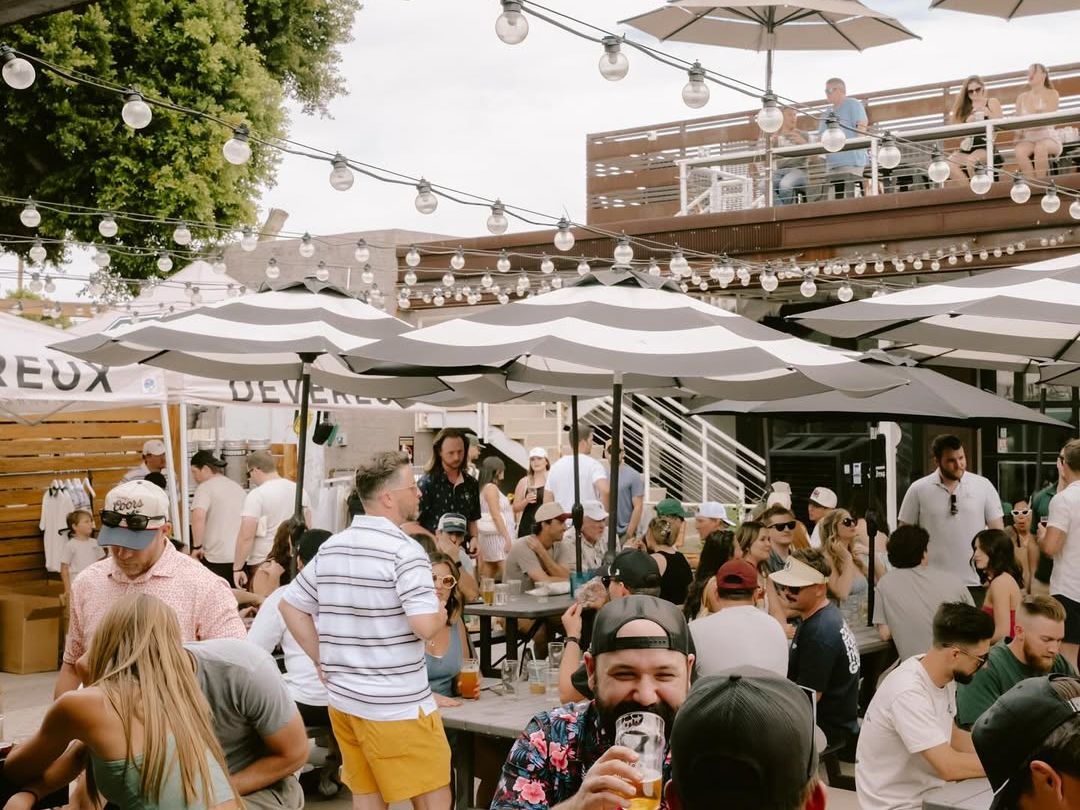 Guests gather outdoors at Goldwater Brewing Co., enjoying craft beer in a lively Scottsdale taproom. String lights, shared tables, and a relaxed crowd create a fun local brewery vibe.