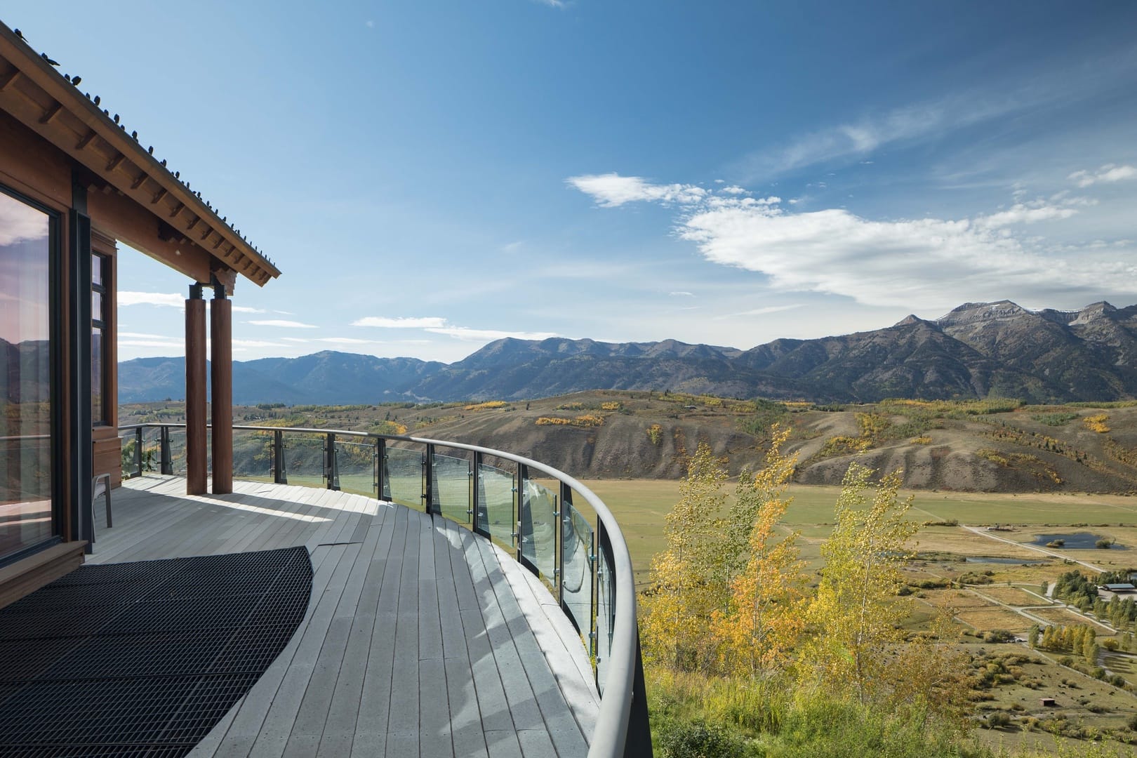 Mountain View Escape features a curved private deck overlooking a wide valley and rugged mountain peaks. Guests can take in the peaceful scenery and changing seasons from this scenic outdoor space.