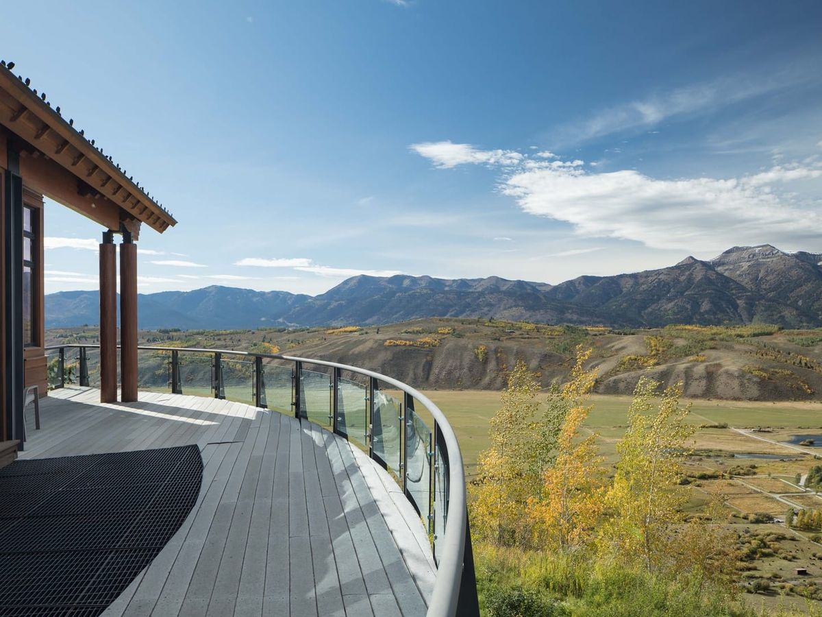 Mountain View Escape features a curved private deck overlooking a wide valley and rugged mountain peaks. Guests can take in the peaceful scenery and changing seasons from this scenic outdoor space.