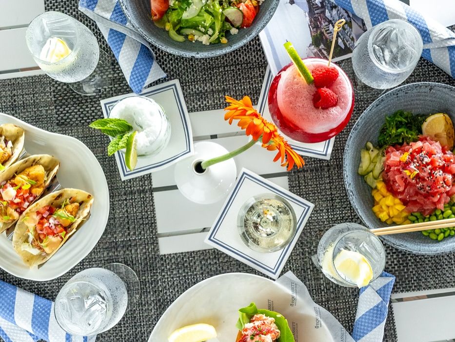 An elegant plated entrée featuring steak topped with bacon-wrapped scallops and served with broccolini and creamy sauce. The dish highlights the refined style of fine dining restaurants. Meals like this showcase the rich seafood and farm flavors of the region.