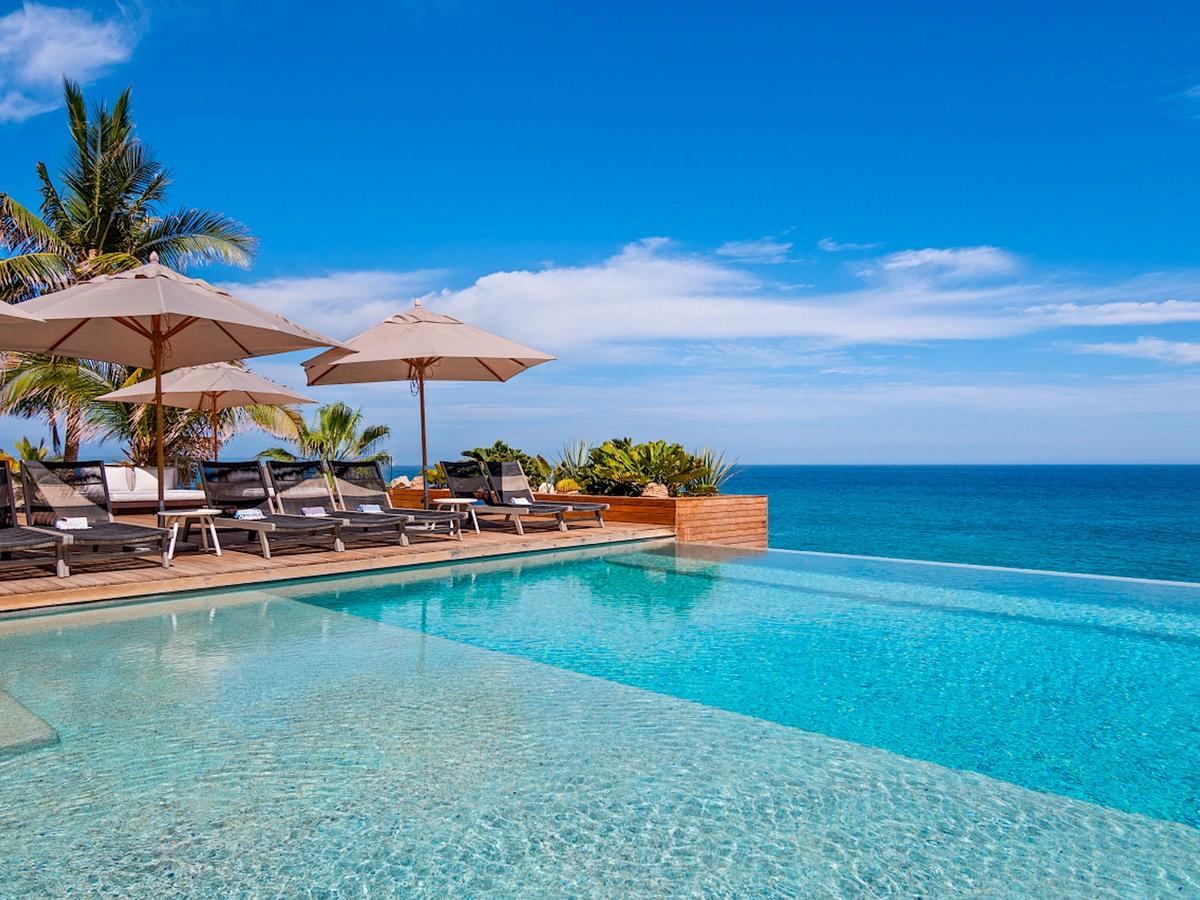 Resort pool with tan umbrellas and lounge chairs beside it