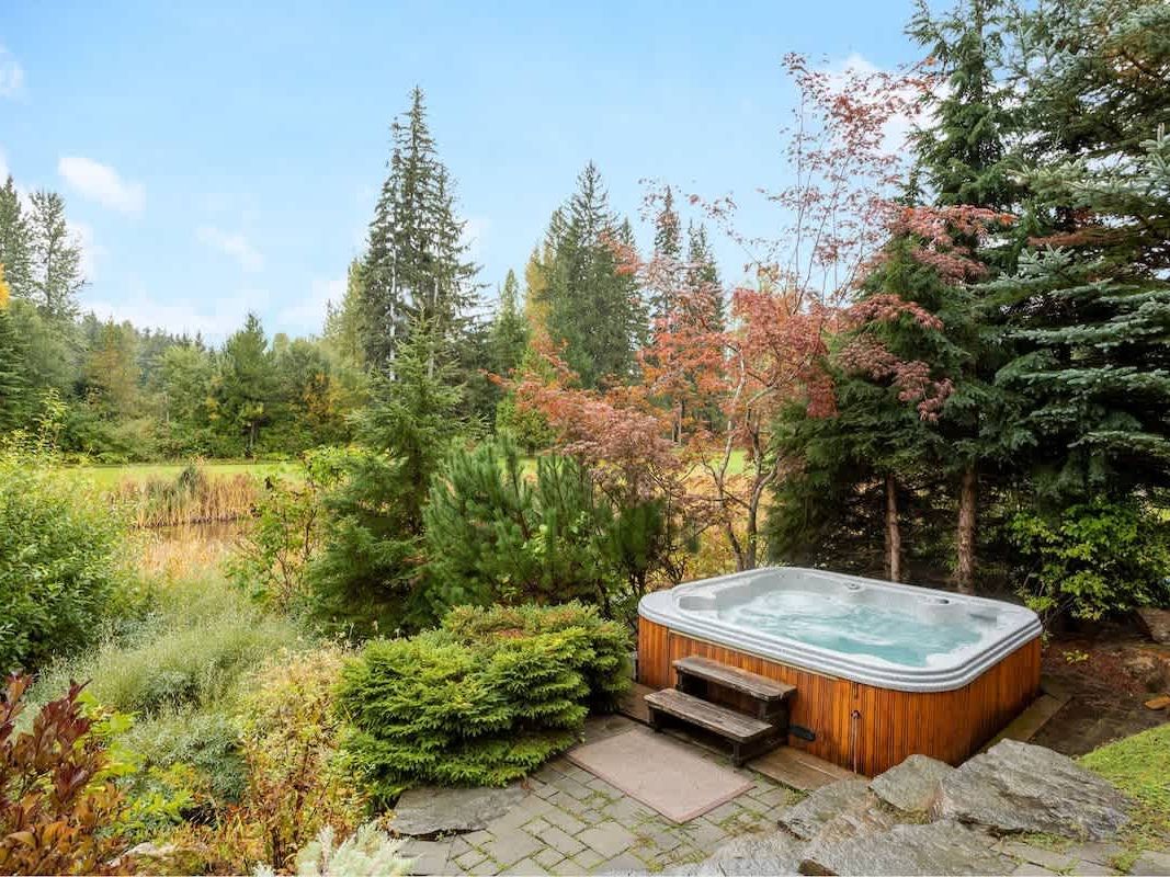 Outdoor hot tub tucked into a peaceful mountain setting with tall trees, colorful foliage, and open views of nature. This private spa area gives the cabin a quiet and cozy feel for a relaxing getaway.