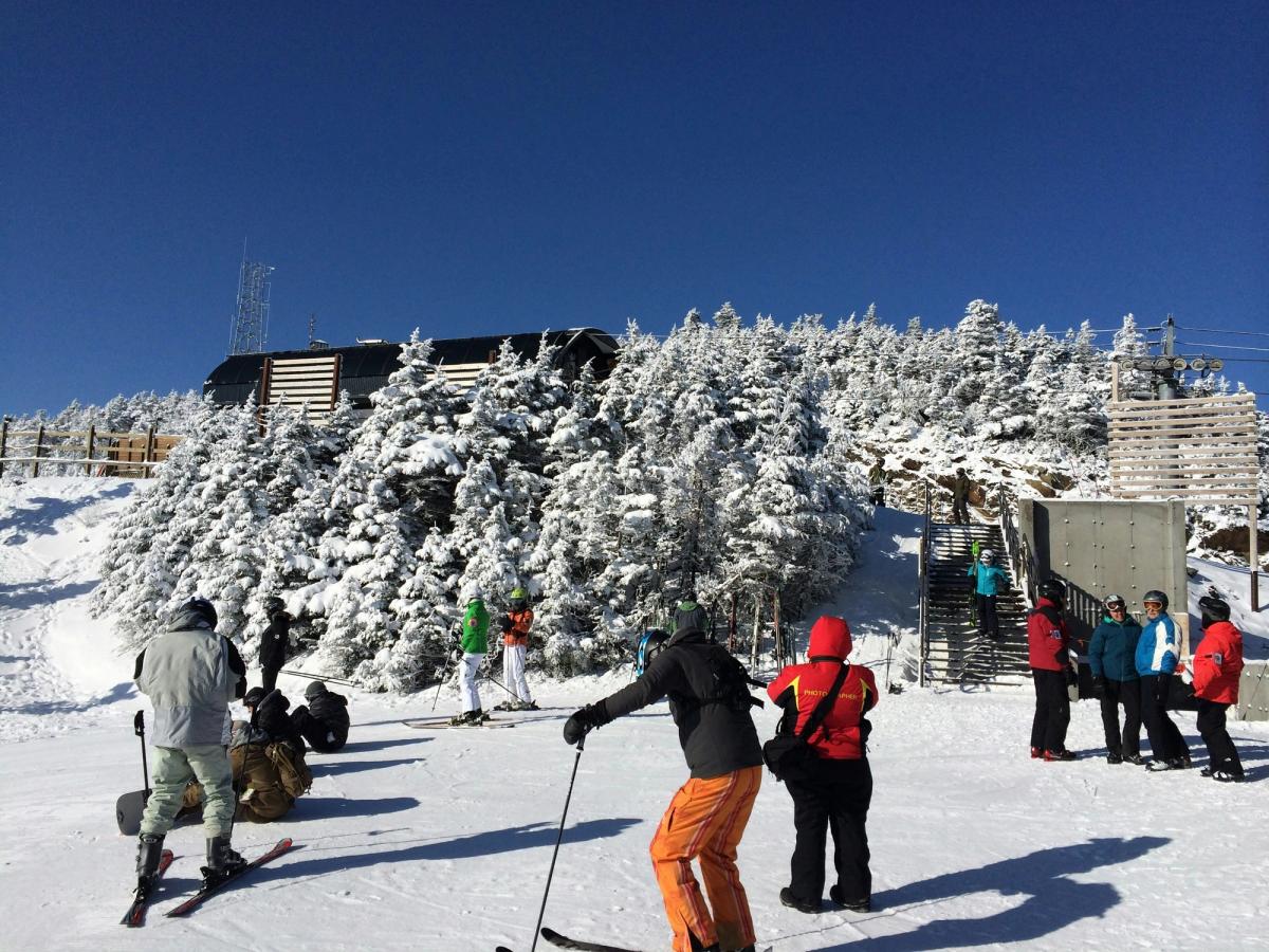 group of people in ski wear and ski gear in front of snowy trees and building in vermont