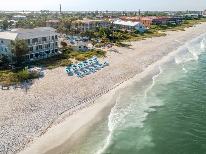 Aerial view of the beach and vacation rental that overlooks the water and beach service with umbrellas