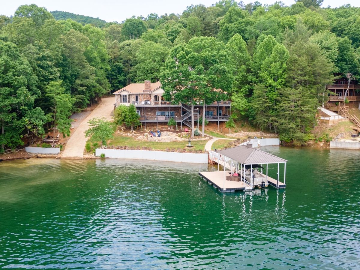 A spacious lakefront lodge with a private dock sits nestled in thick trees. It’s built for big family trips and water fun from sunrise to sunset.