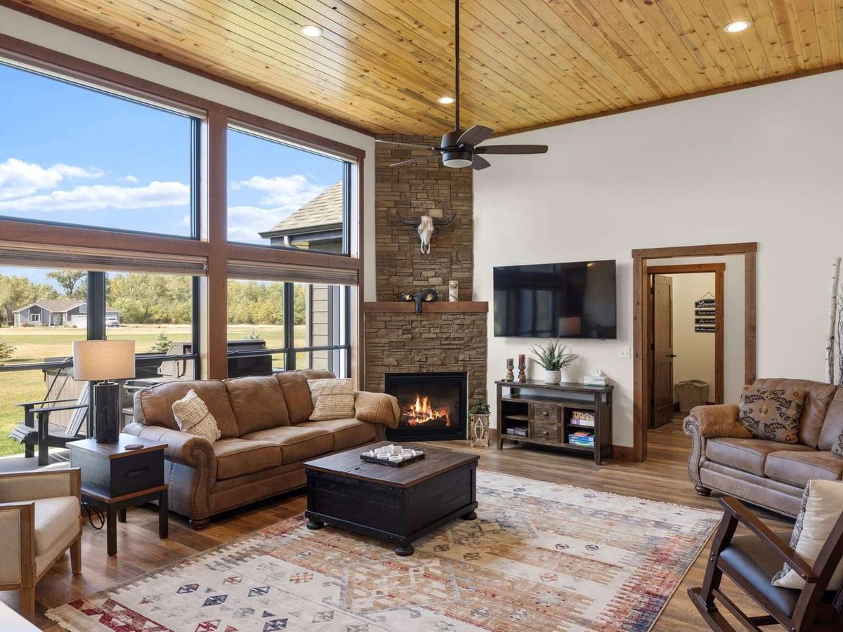 With stone accents, vaulted ceilings, and huge windows framing open skies, this lodge-style living room feels both rustic and refined. It’s the kind of place you gather with family by the fire after a day outdoors.