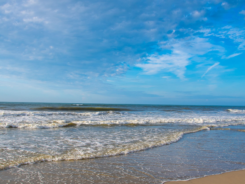 Gentle waves roll onto the sandy shore of Topsail Beach under a bright blue sky. It’s a quiet, relaxing place perfect for beach walks, shell hunting, and sunbathing.