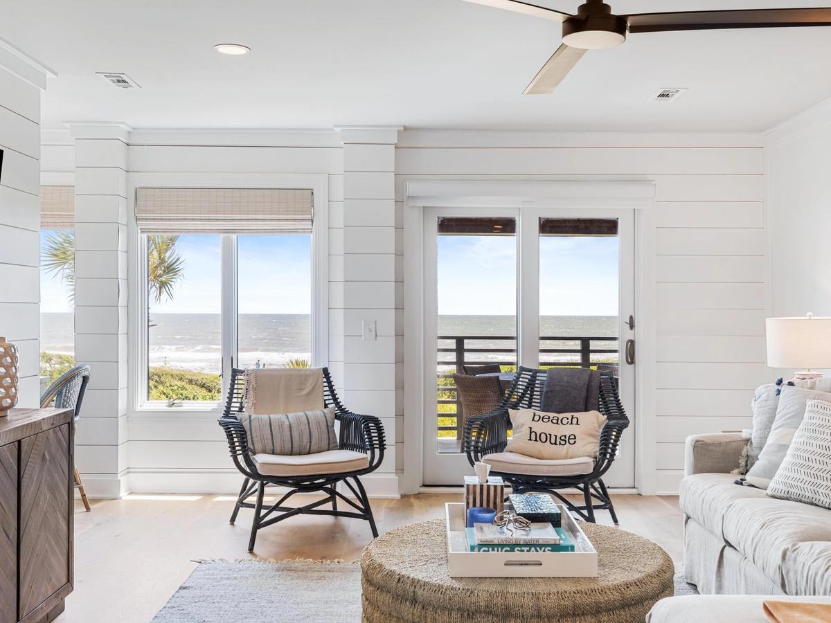 Interior of Akers Ellis home with two beach chairs and ouch with windows overlooking ocean