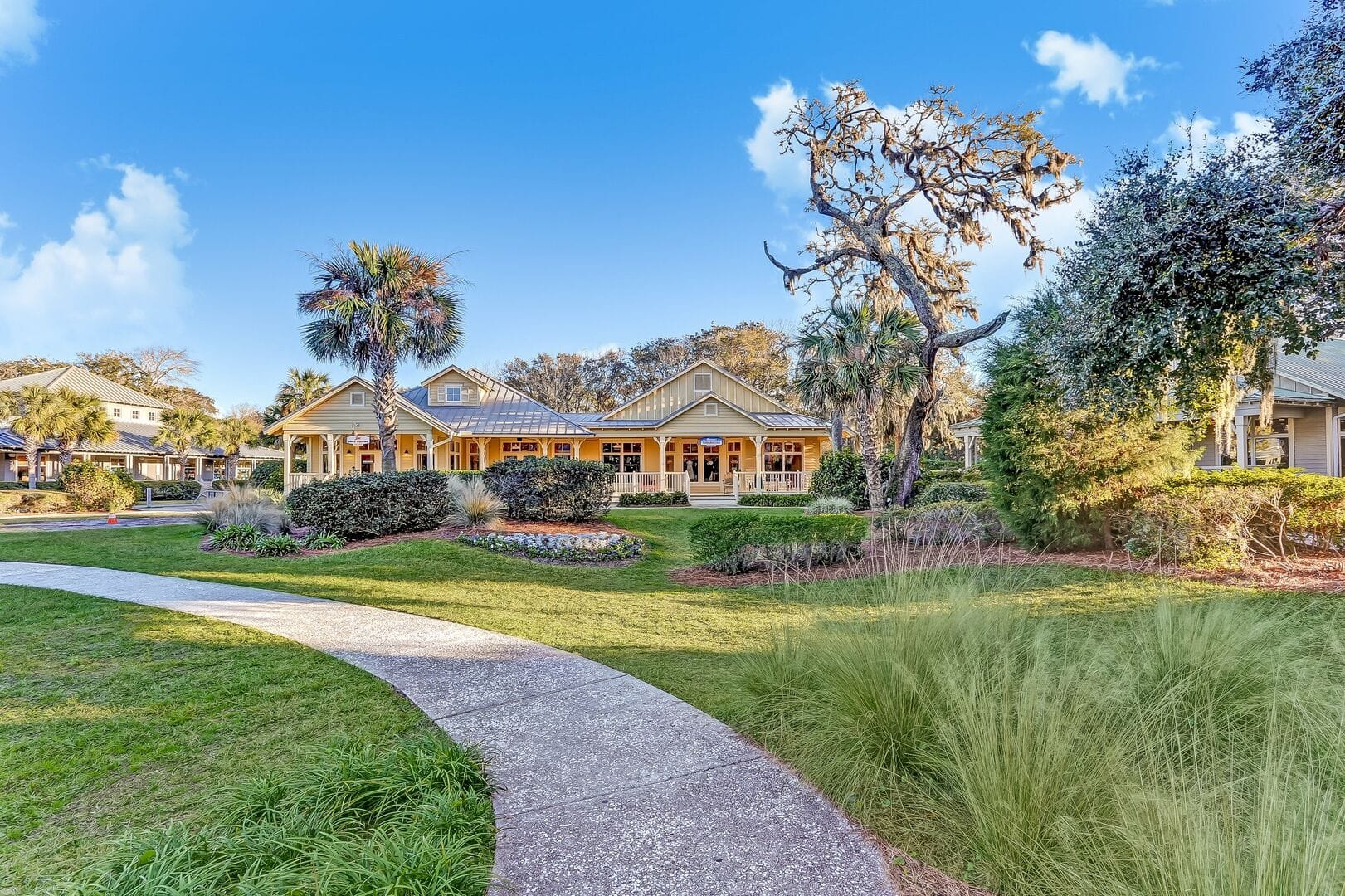 A beautiful coastal cottage on Amelia Island with palm trees, manicured gardens, and a welcoming front porch. The soft sunlight and relaxed charm make it perfect for a beach getaway.
