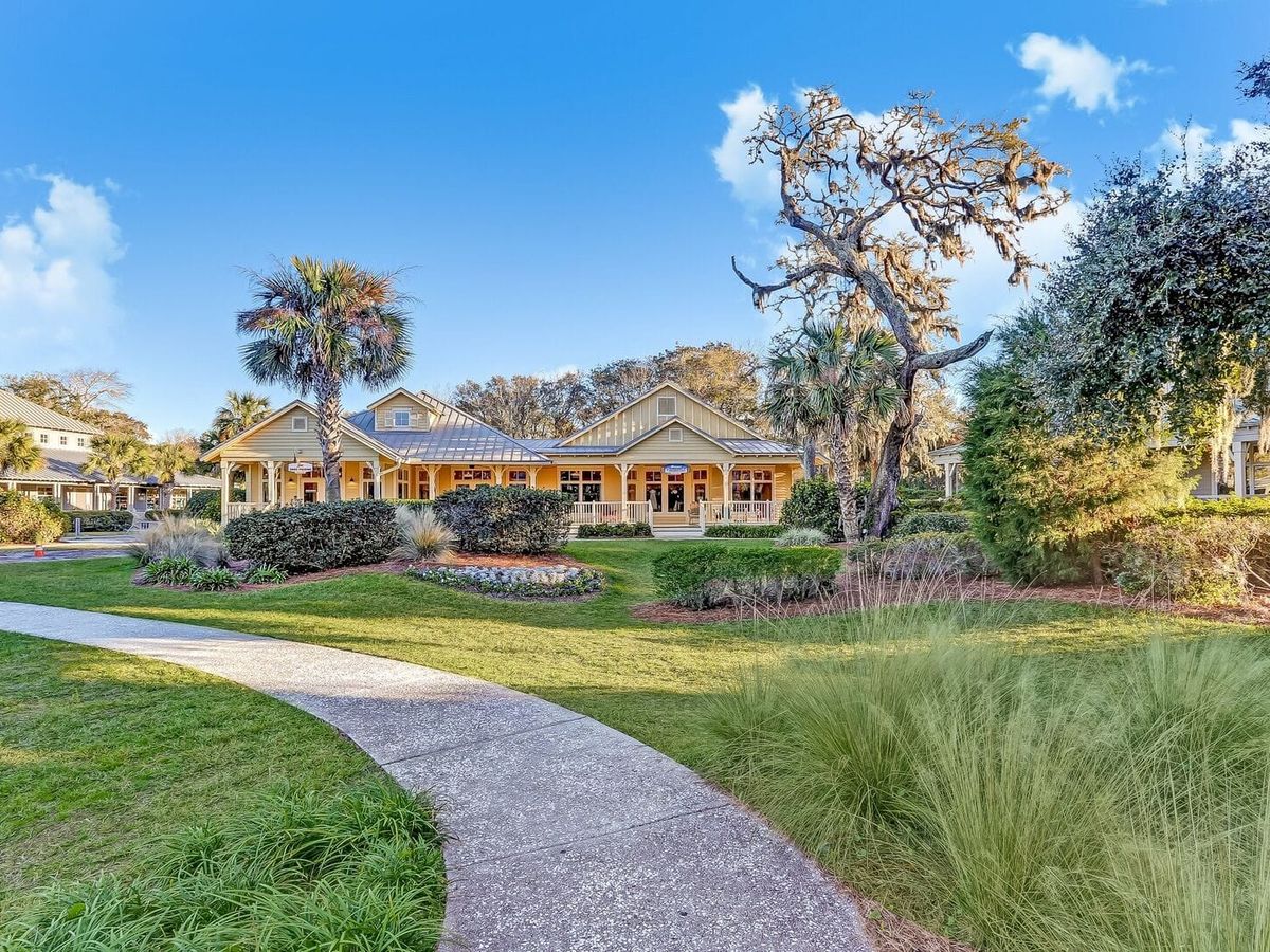 A beautiful coastal cottage on Amelia Island with palm trees, manicured gardens, and a welcoming front porch. The soft sunlight and relaxed charm make it perfect for a beach getaway.