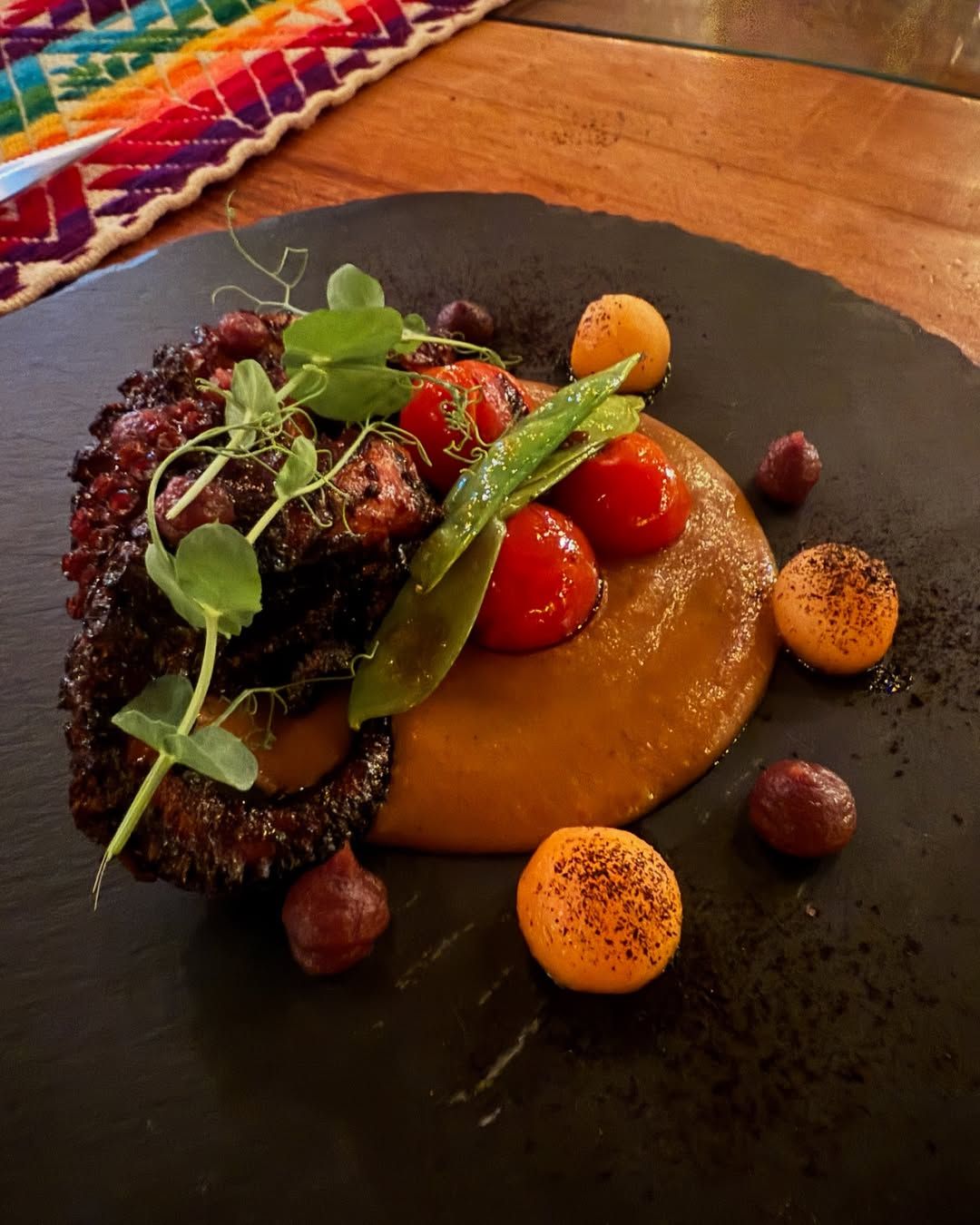 A vibrant plate of grilled octopus is paired with roasted vegetables and a rich, earthy sauce at Metate, celebrating traditional Mexican flavors with a modern twist. The presentation is as beautiful as it is flavorful, showcasing the artistry of Cabo’s culinary scene.