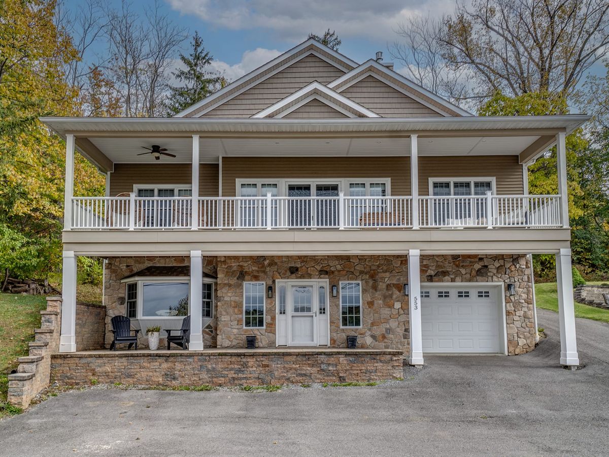 A welcoming winery patio with picnic tables and red chairs overlooking rolling Finger Lakes views at sunset. It’s a popular place to enjoy local wine, live music, and laid-back evenings with friends.