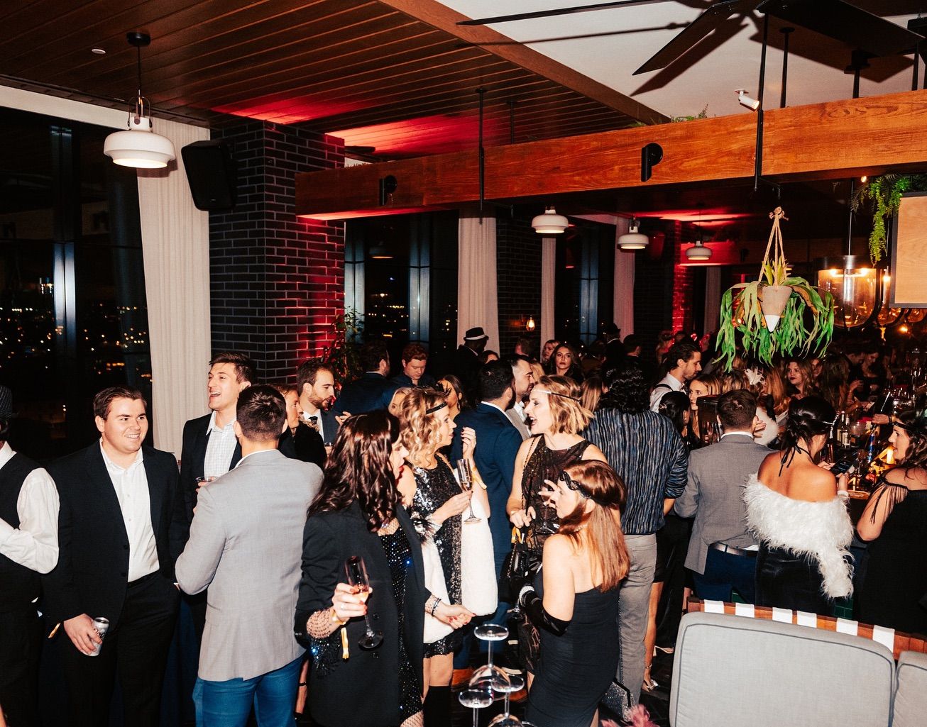 A lively rooftop party at Virgin Hotels Nashville with guests dressed up, chatting, and enjoying drinks under warm city lights. This stylish venue is popular for nightlife, social events, and skyline views in downtown Nashville.