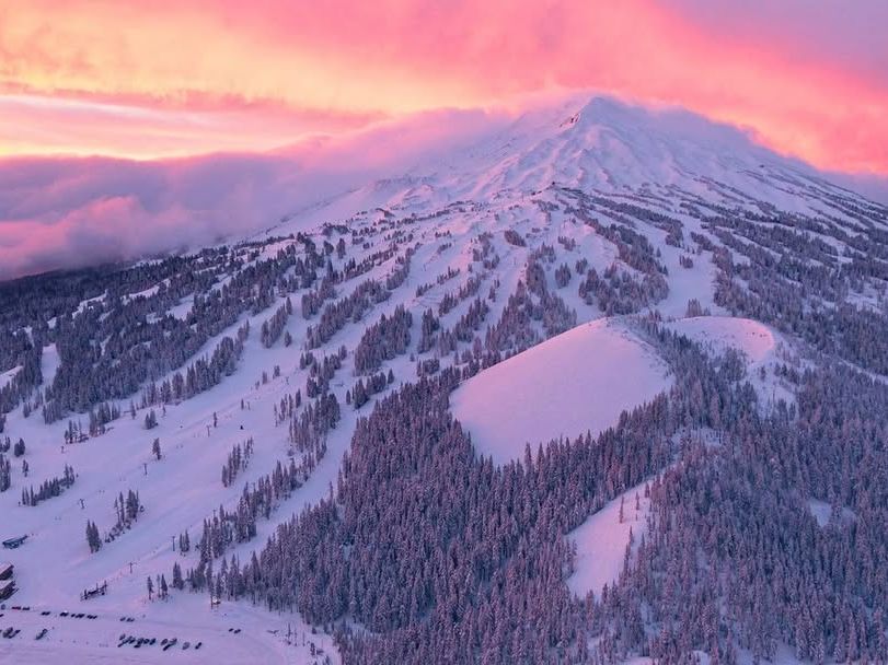 Snow-covered Mount Bachelor glowing under a breathtaking pink and orange sunset, perfect for skiing and winter adventures