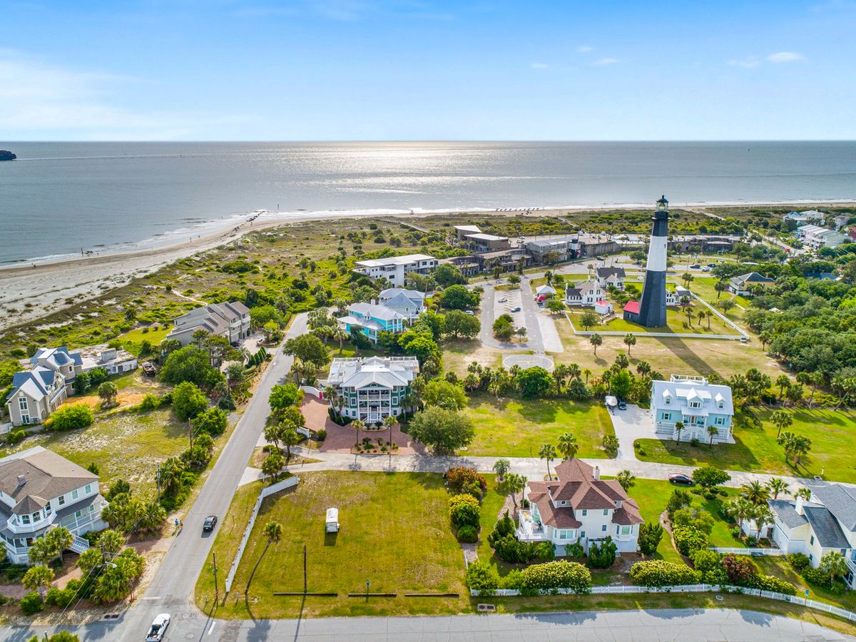 Aerial view of lighthouse and vacation homes surrounding it with beach and ocean in the background