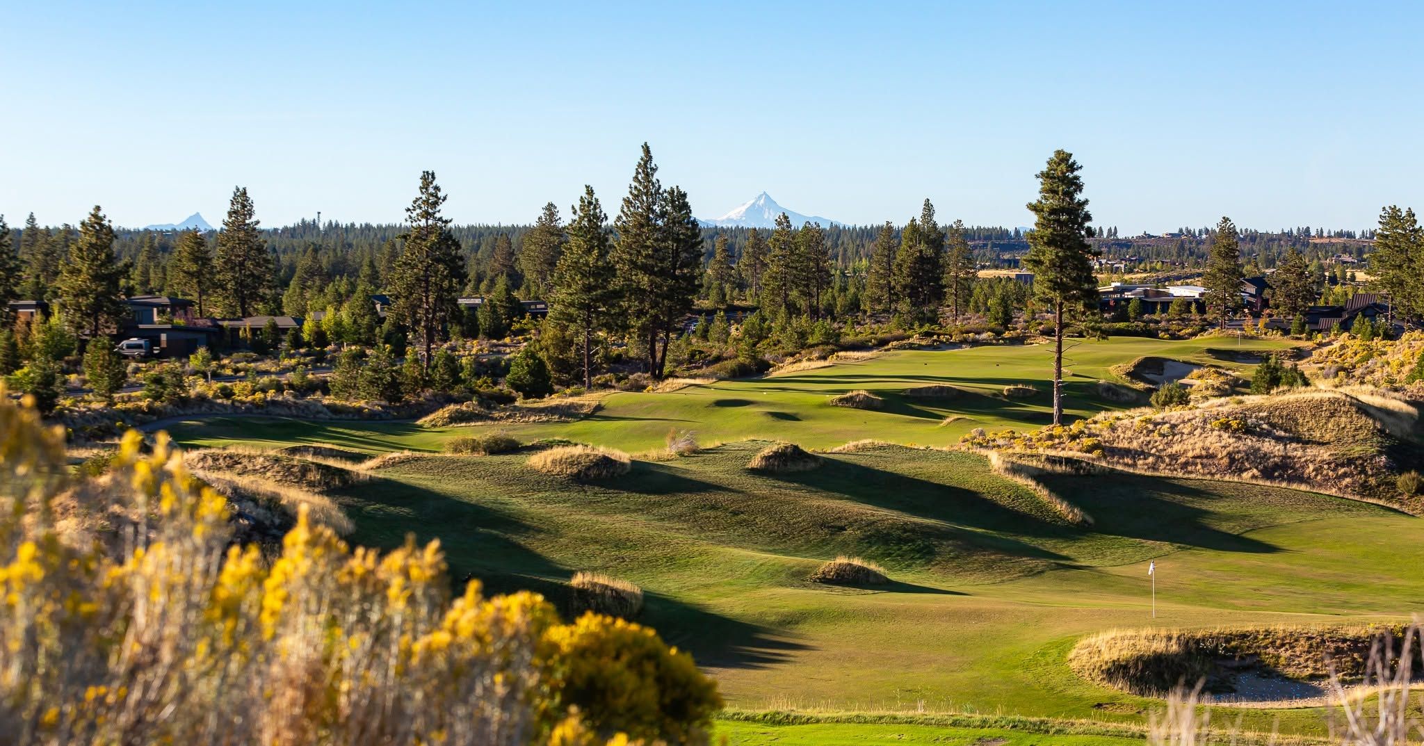 Rolling fescue-lined fairways and native sagebrush define the dramatic links-style layout of Tetherow Golf Club in Bend, Oregon, with snow-capped Mount Jefferson rising above the pine forest on the horizon. 