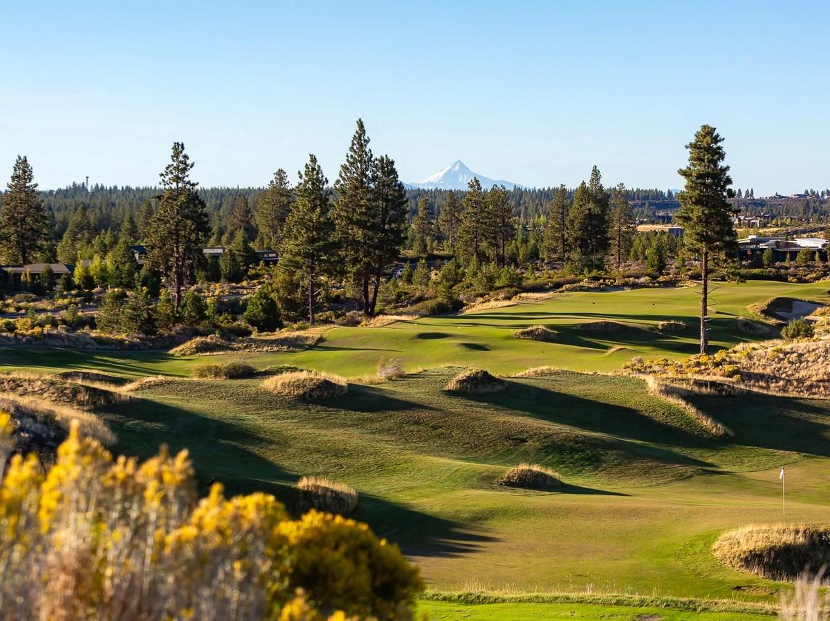 Rolling fescue-lined fairways and native sagebrush define the dramatic links-style layout of Tetherow Golf Club in Bend, Oregon, with snow-capped Mount Jefferson rising above the pine forest on the horizon.