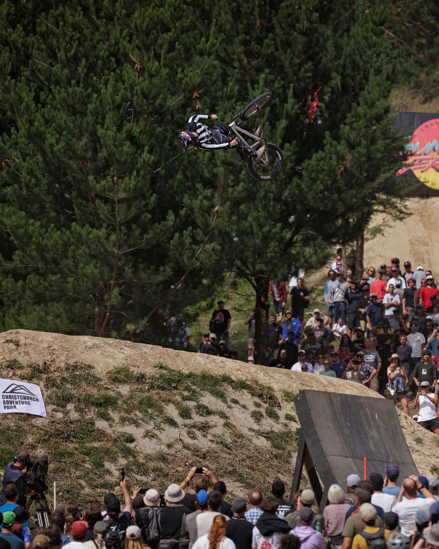 A mountain biker performs an impressive trick high in the air during the Crankworx competition. Spectators gather around the dirt course to watch the exciting stunt. Crankworx is one of Whistler’s biggest summer mountain biking festivals.