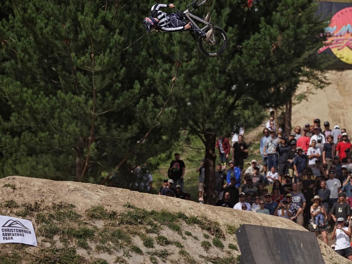 A mountain biker performs an impressive trick high in the air during the Crankworx competition. Spectators gather around the dirt course to watch the exciting stunt. Crankworx is one of Whistler’s biggest summer mountain biking festivals.