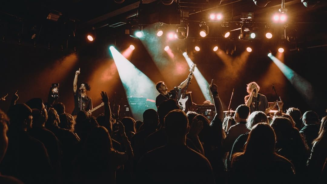 A band rocks the stage under warm lights while the crowd raises their hands and sings along. The energy in the room feels electric, with people fully locked into the music. It’s a perfect capture of Nashville’s live-music spirit.