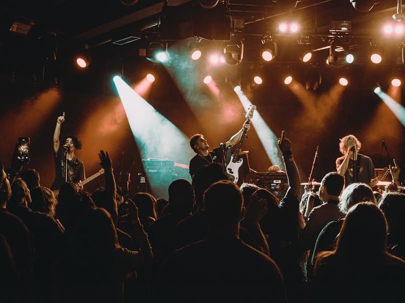 A band rocks the stage under warm lights while the crowd raises their hands and sings along. The energy in the room feels electric, with people fully locked into the music. It’s a perfect capture of Nashville’s live-music spirit.