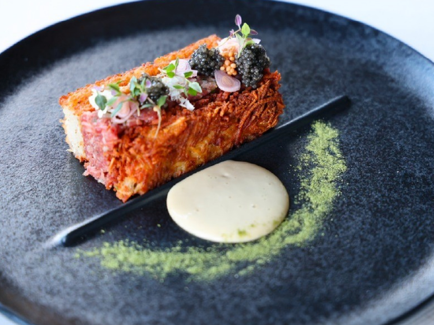 Delicious chef plate on black plate with green sprinkle and white sauce in a circle