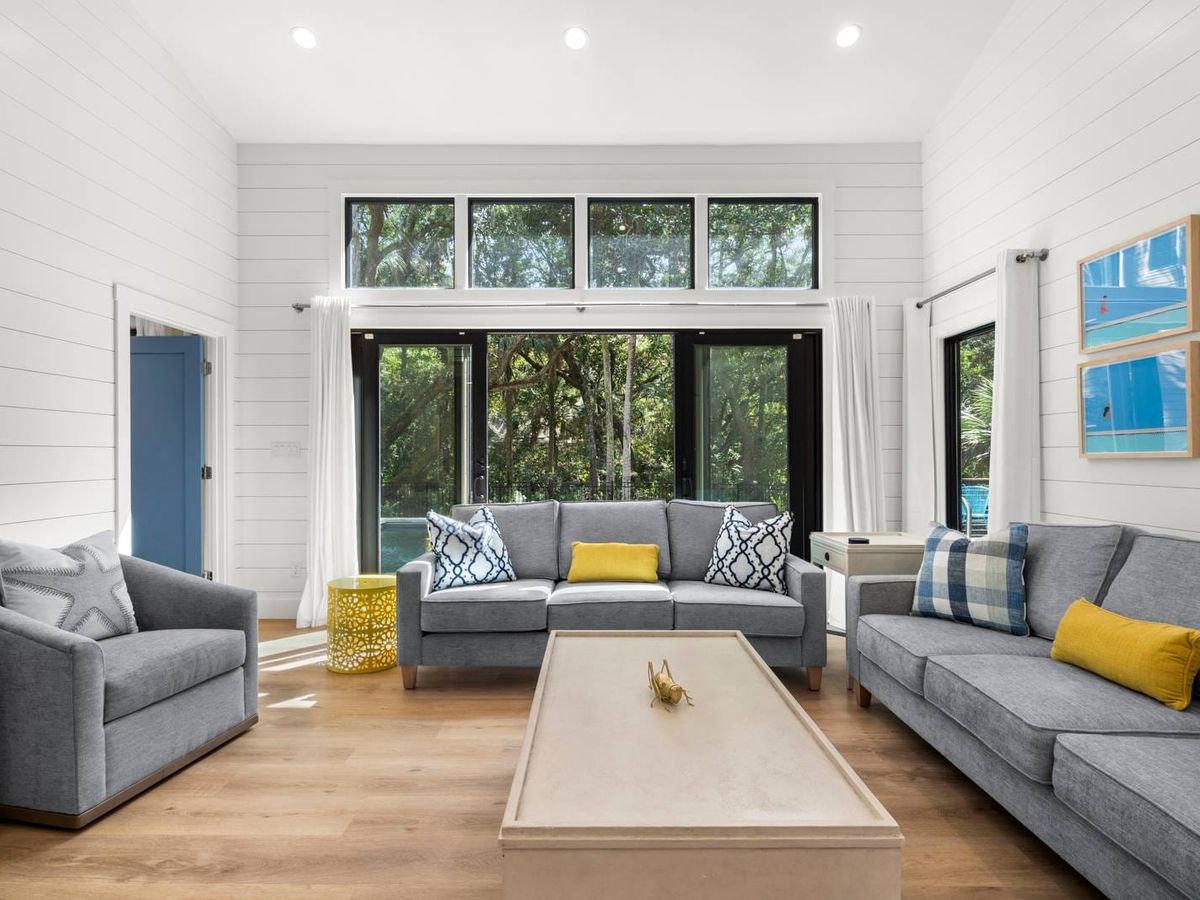A bright, coastal-inspired living room with pastel seating, modern beach décor, and an open layout perfect for family gatherings. Steps away from the beach and full of comfort.