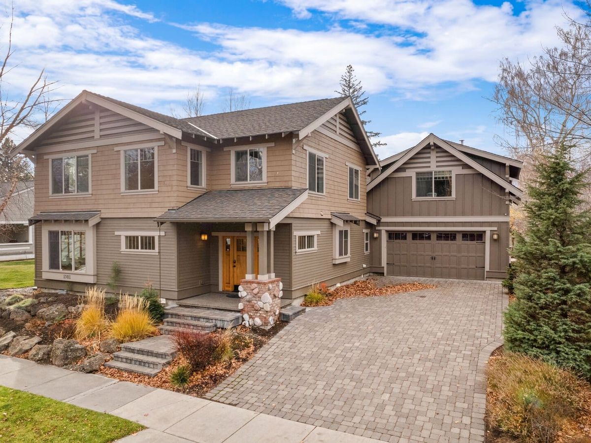 A beautifully crafted mountain home with a spacious driveway and landscaped front yard framed by evergreens. Its earthy tones and large windows give it a cozy yet modern feel ideal for family stays.